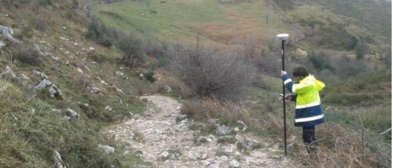 Un operario hace mediciones en el sendero de La Flecha, en Gamonéu.