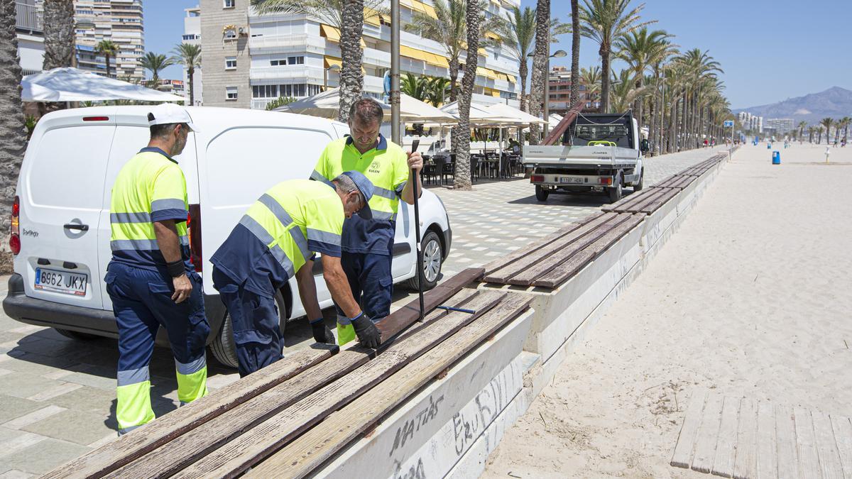 Un grupo de operarios arreglando a primera de la tarde de este martes banco en el paseo de la playa de San Juan.