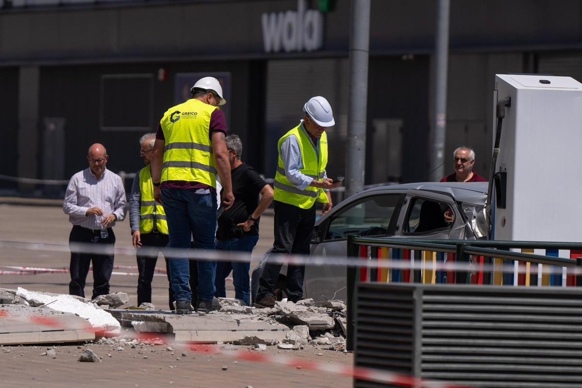 Técnicos valoran los daños producidos en la fachada de la Galerías Tresillo en Via Sabadell. En la foto, el coche eléctrico afectado