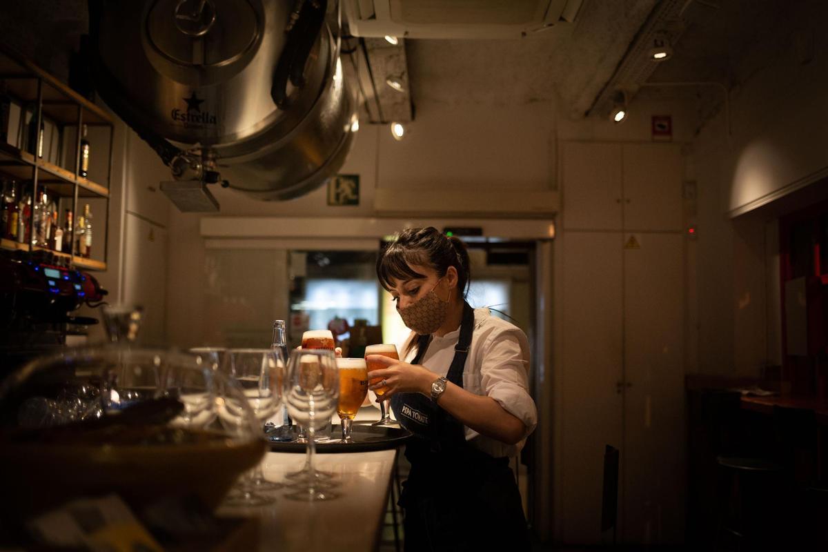 Una camarera sirve una cerveza en el interior de un bar.