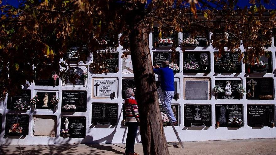 Una pareja coloca flores en una tumba del cementerio de Antequera en las vísperas de la conmemoración de los difuntos.