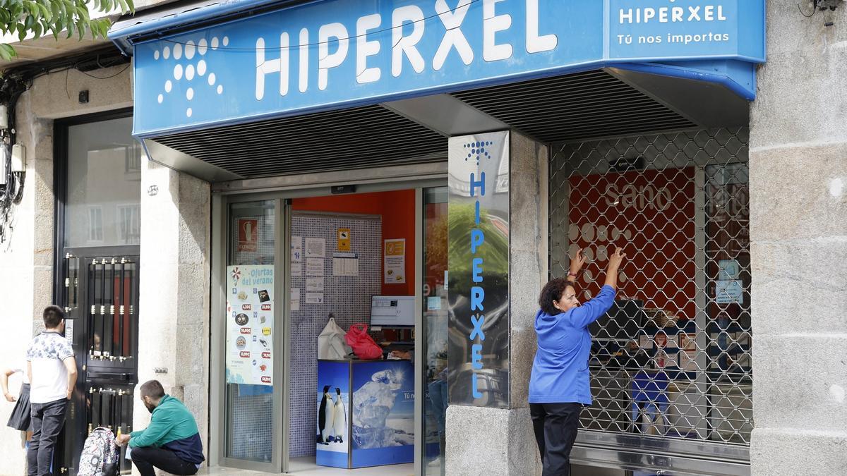 Una empleada de Hiperxel baja la verja de una de las tiendas de Vigo