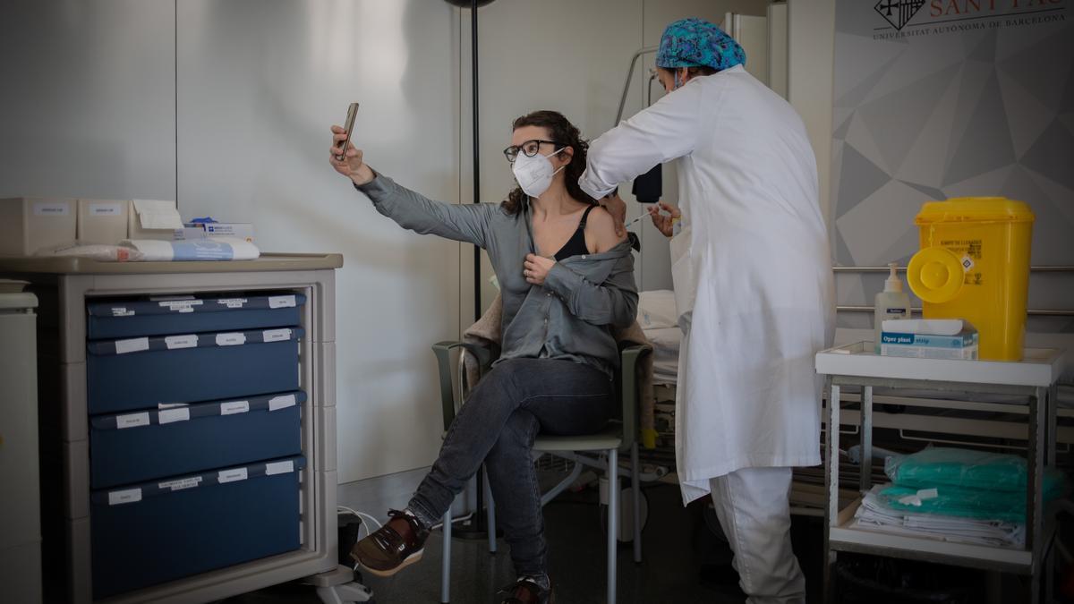 Una enfermera administra la vacuna a una profesional sanitaria, que se hace un &#039;selfie&#039;.
