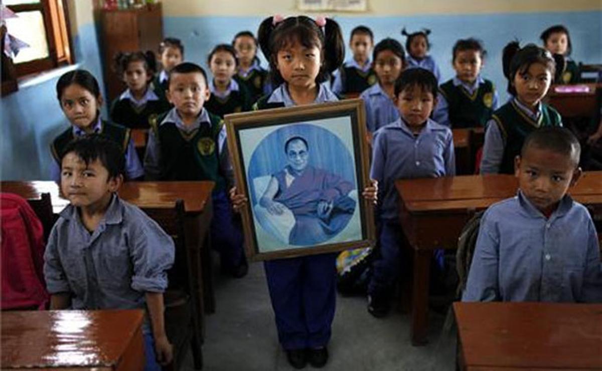 Una nena sosté davant dels seus companys de classe el retrat del líder espiritual tibetà, el dalai-lama, en una escola de Dharmsala, al nord de l’Índia.