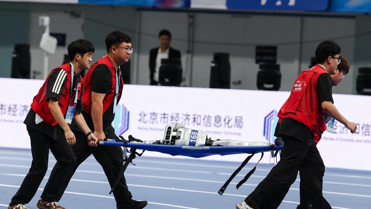 Unos operarios retiran de la pista a un robot humanoide en Pekín.