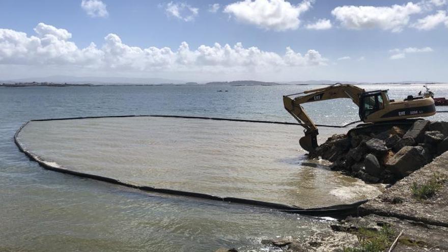 Una retroexcavadora se adentra en el mar para acabar de desmantelar el muelle en A Ribeiriña / Suso souto