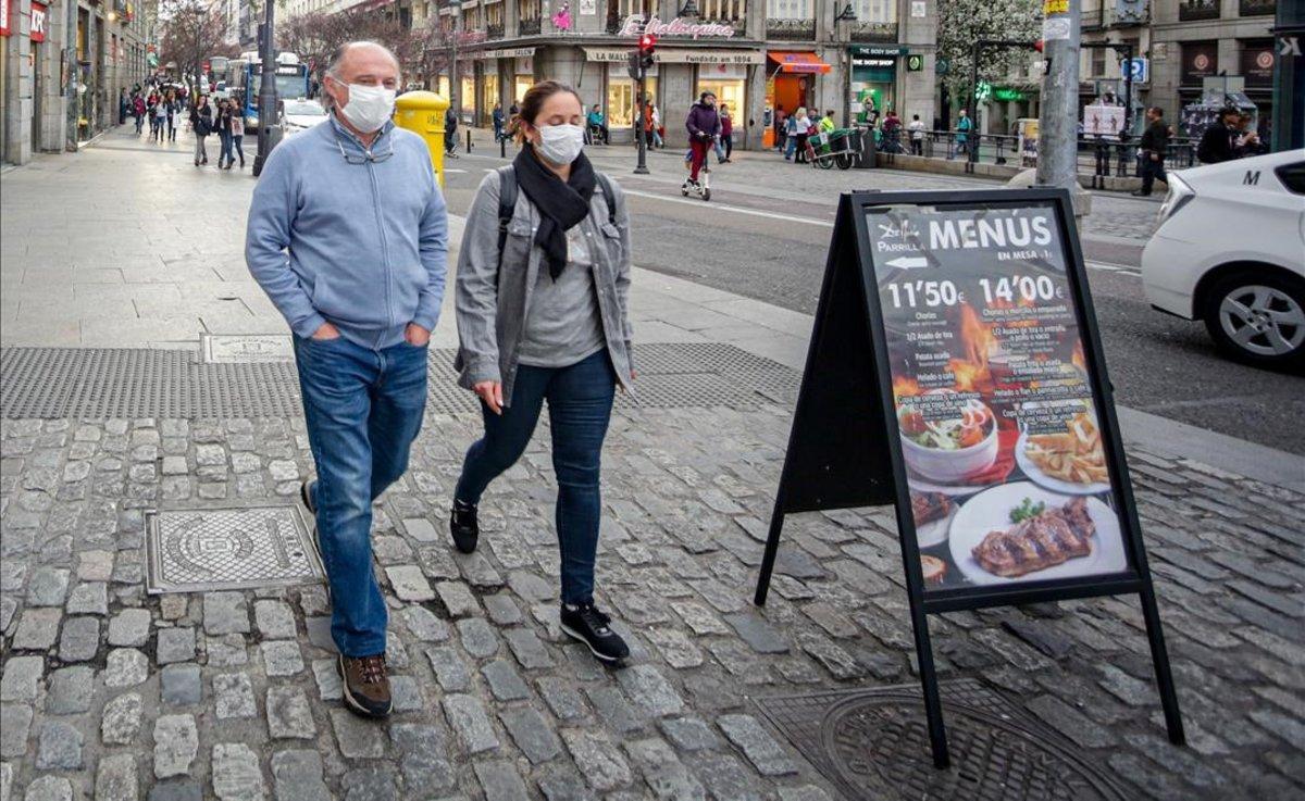 Dos personas con mascarillas por temor al coronavirus en el centro de Madrid.