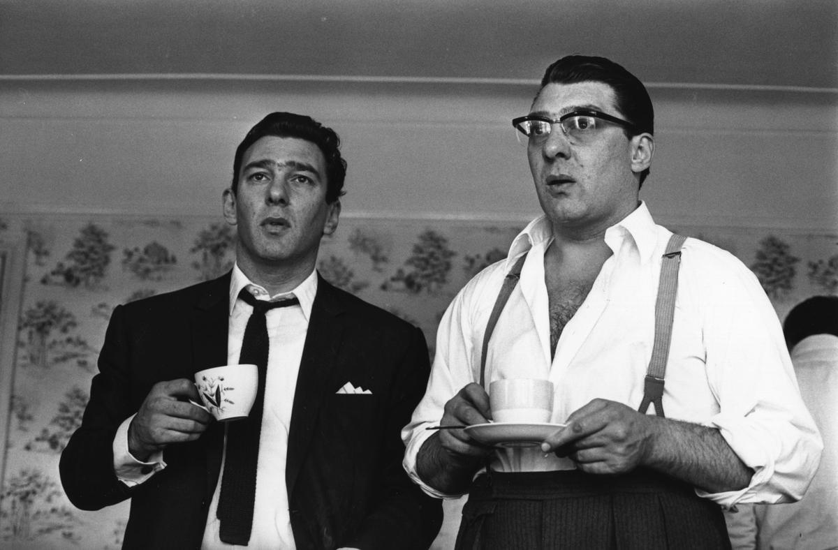 Reggie (izquierda) y Ronnie Kray toman una taza de té en la casa de sus padres en Bethnal Green, en 1966.