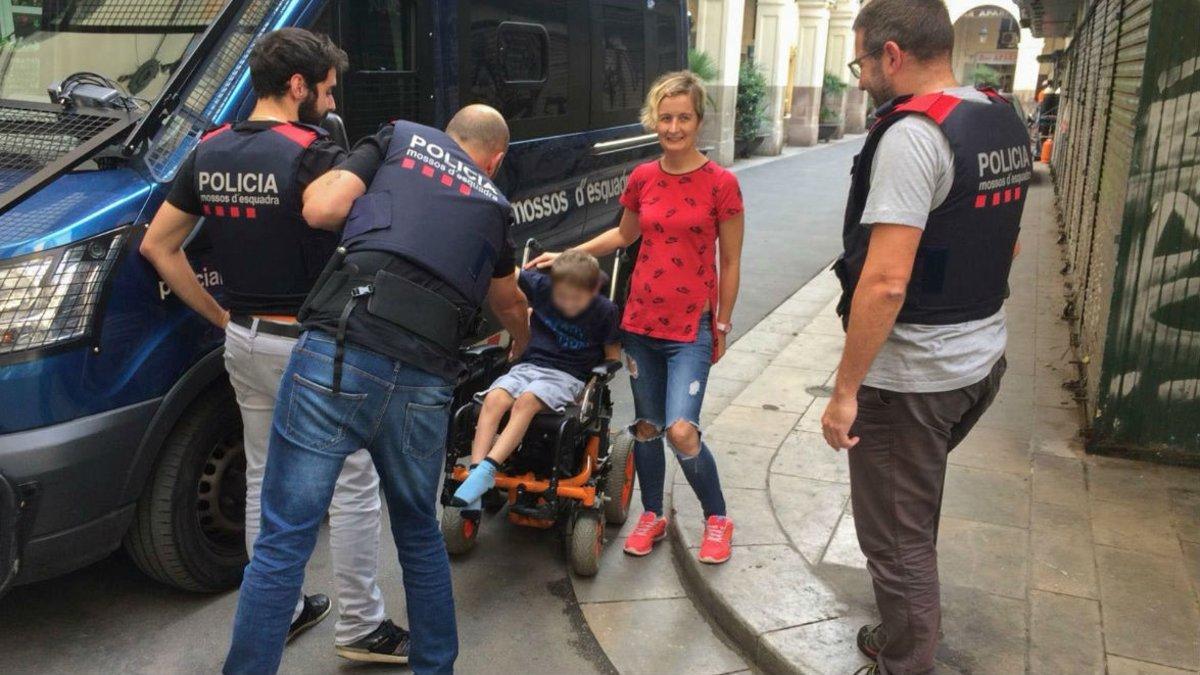 Tres agentes de los Mossos entregan la silla de ruedas robada a sus propietarios, en Sant Andreu