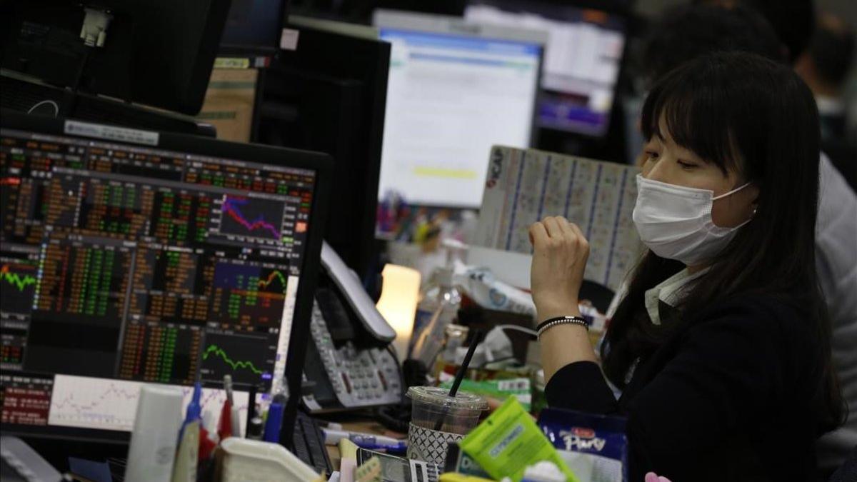 Una agente de bolsa trabaja con máscara protectora en Seúl
