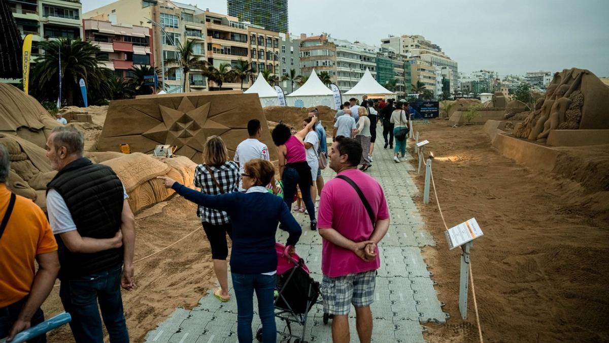 Imagen de varias personas visitando el Belén de Arena de la playa de Las Canteras.