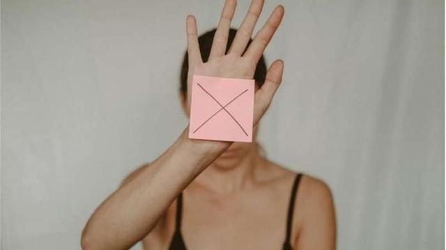 Una mujer oculta su rostro.