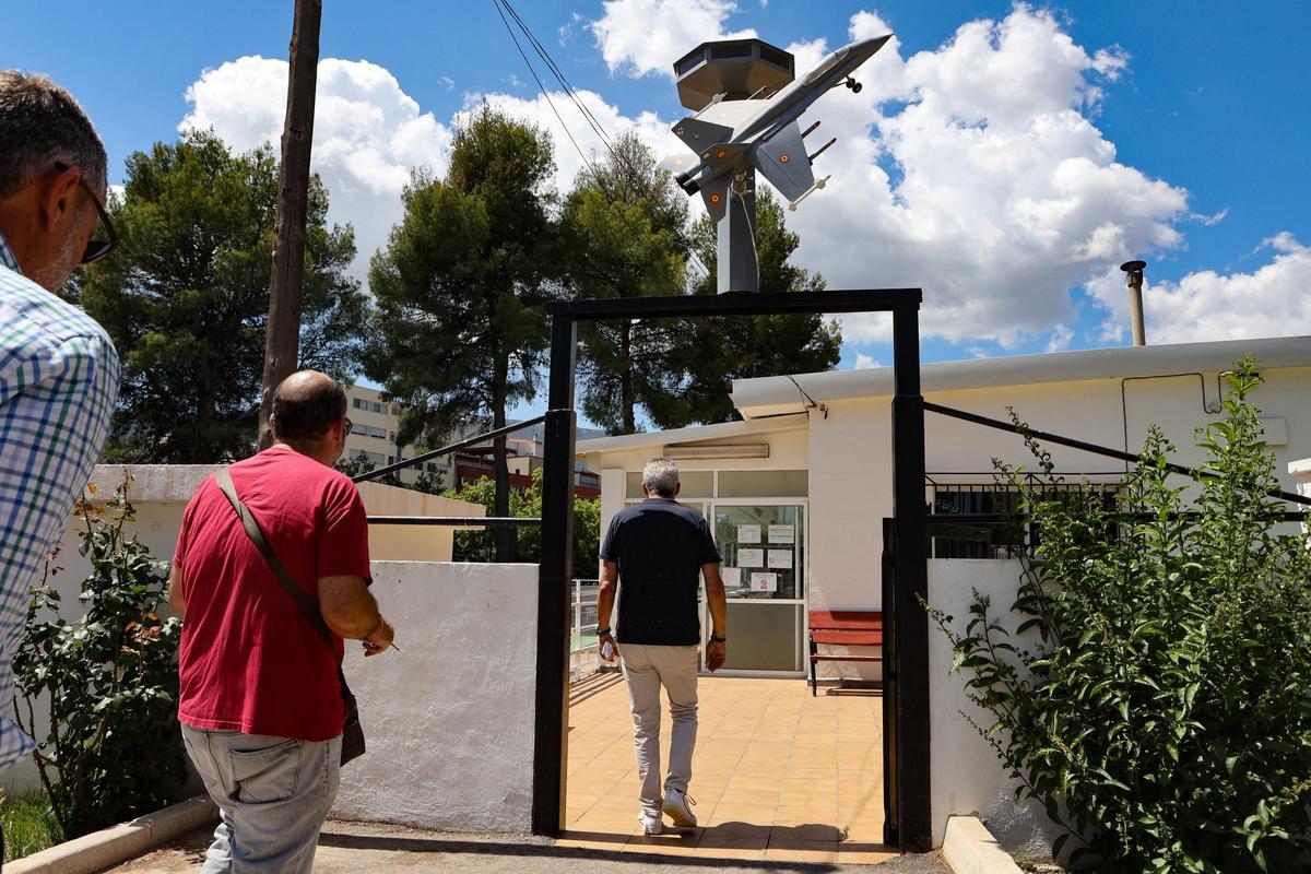 Acceso al centro social construido hace 40 años, con una miniatura de un caza en la entrada