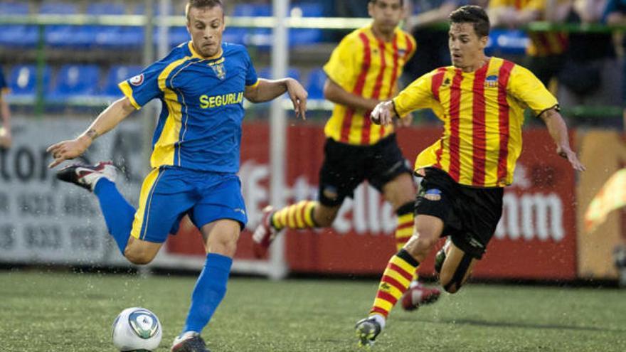 José María Cases arma la pierna derecha para enviar un pase ante la presión de un jugador del Sant Andreu.