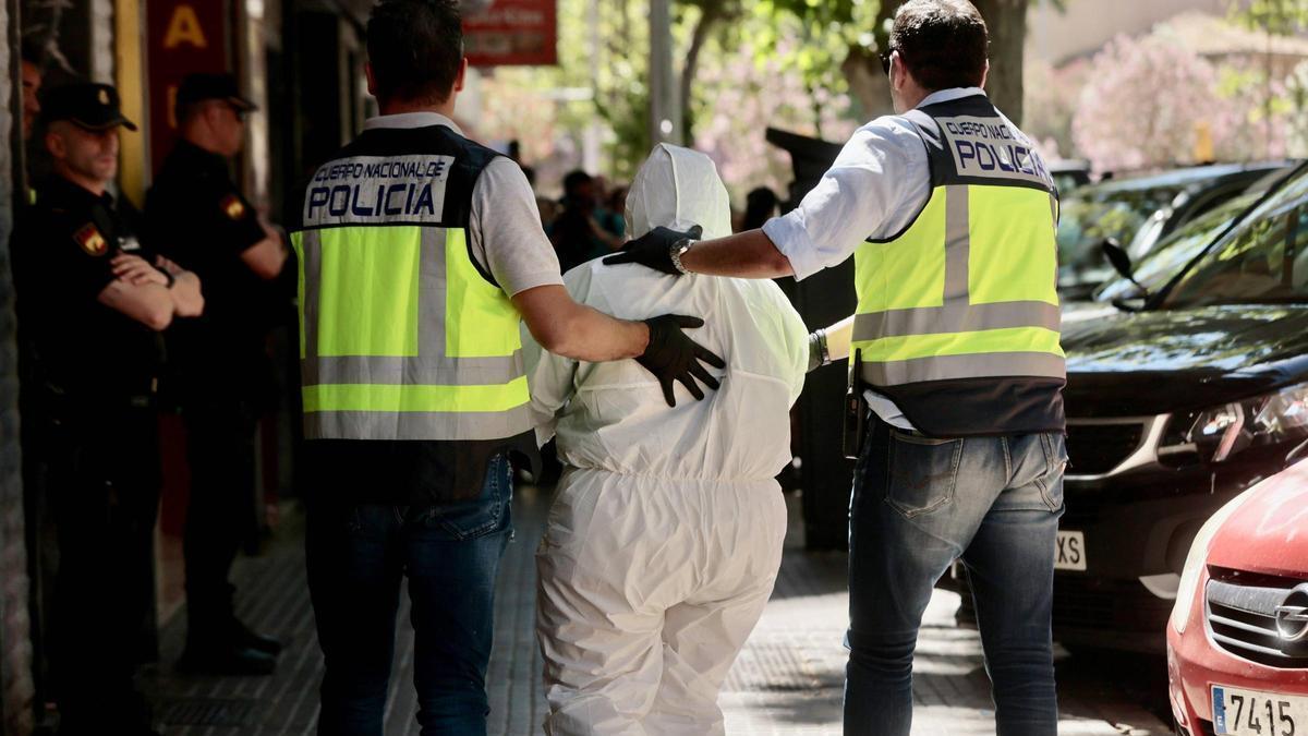 Policías custodian a la detenida durante la reconstrucción del crimen.