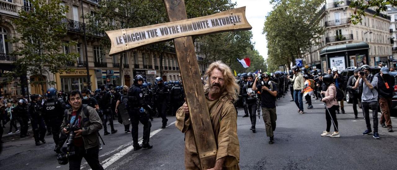 Un manifestante carga con una cruz con el mensaje &#039;La vacuna mata tu inmunidad natural&#039;.