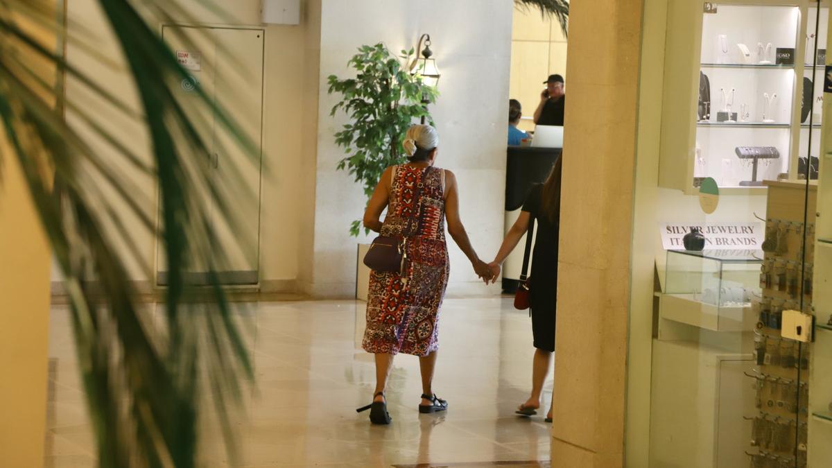 一位来自贝里基布兹的流离失所的老妇人与她的护理人员手拉手进入大卫酒店的餐厅。