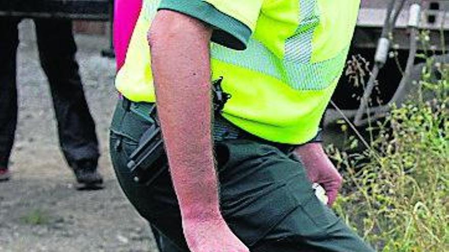 Un guardia civil abandona el lugar del accidente con un disco del tacógrafo en la mano.