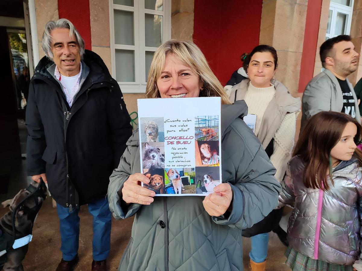 Una vecina muestra un cartel de apoyo a la Protectora de Animais do Morrazo antes del inicio del pleno de Bueu.