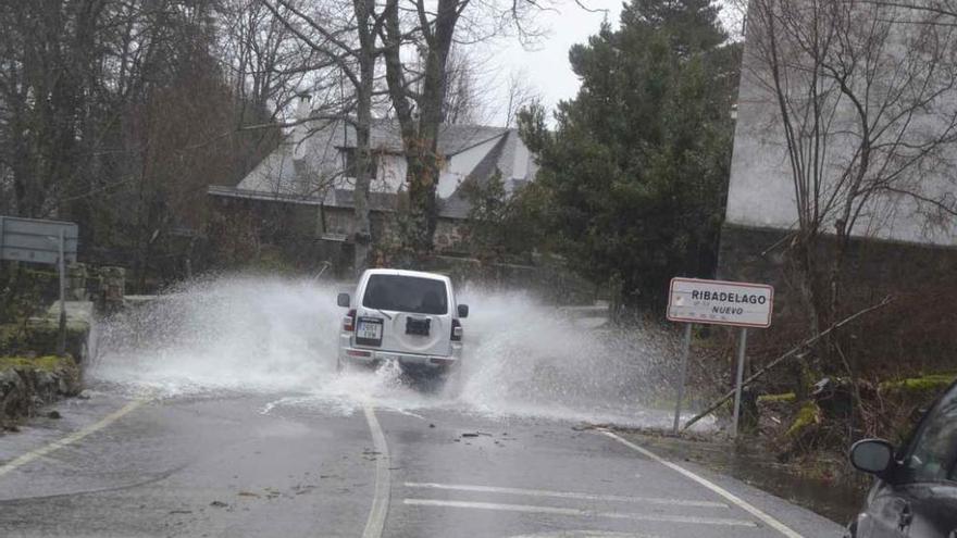 Un coche cruza una corriente de agua en la carretera de Ribadelago Nuevo.
