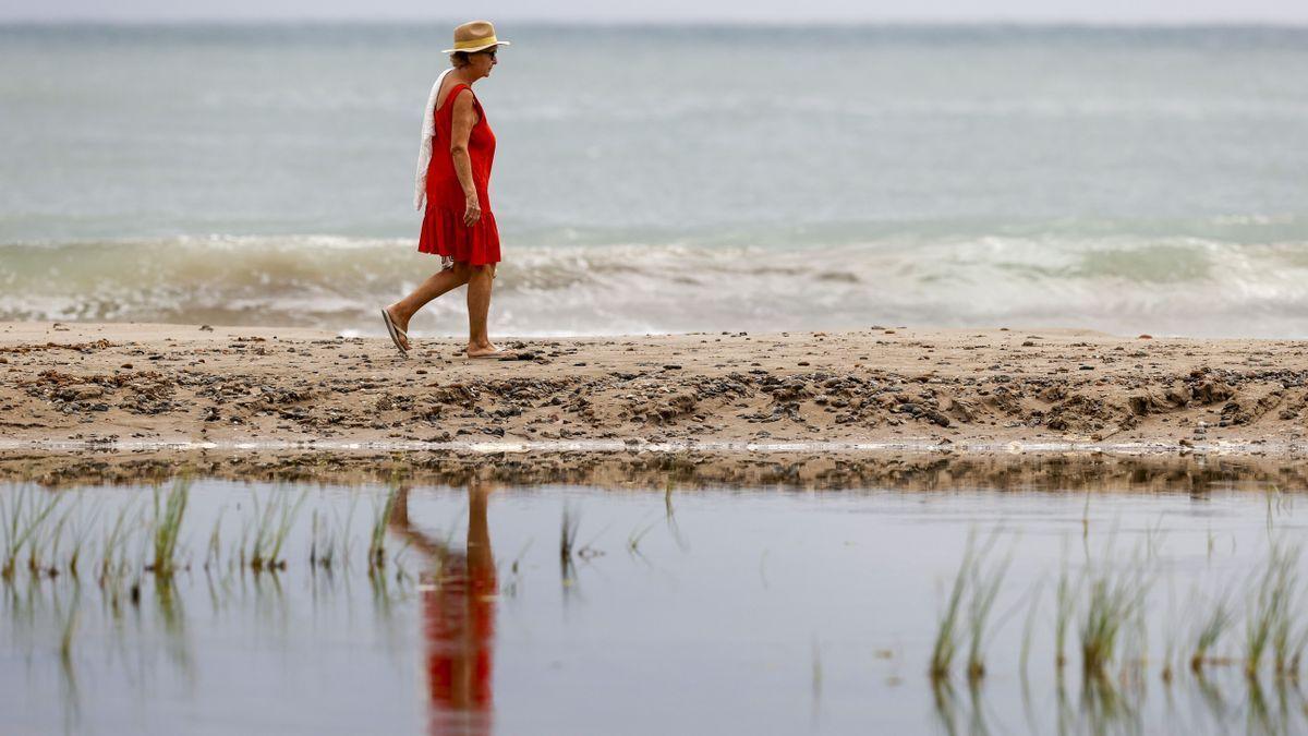 Una mujer pasea en una playa española.