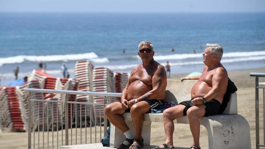 Dos turistas toman sol en un banco de Playa del Inglés, Gran Canaria.