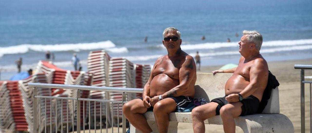 Dos turistas toman sol en un banco de Playa del Inglés, Gran Canaria.