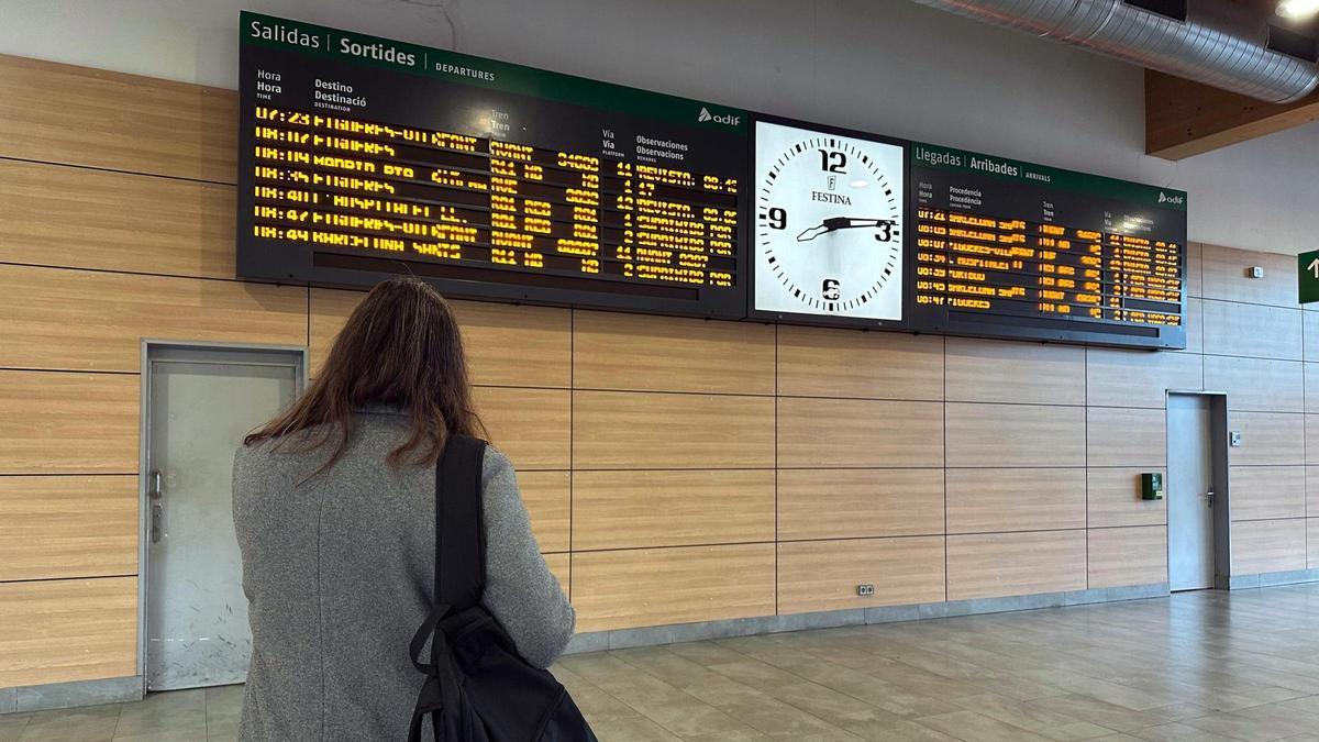 Una dona, a l'estació de Girona, mirant si els AVE surten a l'hora.