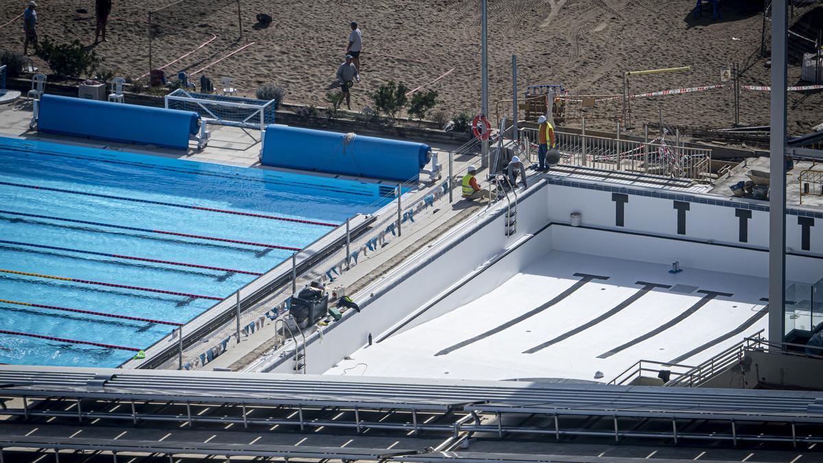Una piscina vacía en obras, a la derecha, junto a otra llena, en Barcelona.