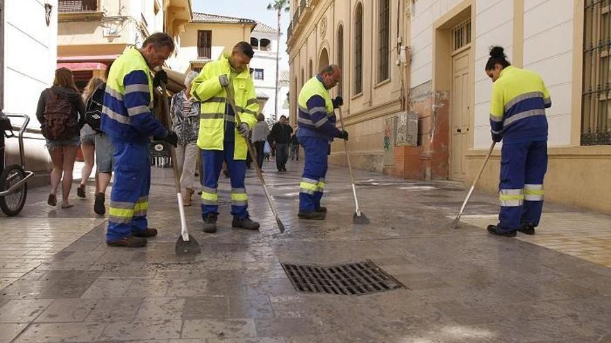 Operarios de Limasa limpian la acera de la Semana Santa.