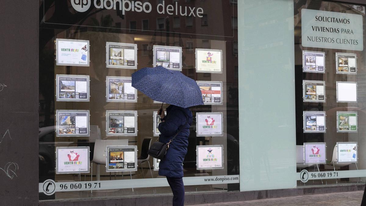 Una mujer examina el escaparate de una inmobiliaria de València