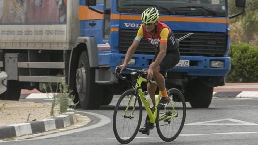 El ciclista en una de las rotondas de la Vía Parque, seguido por un camión.