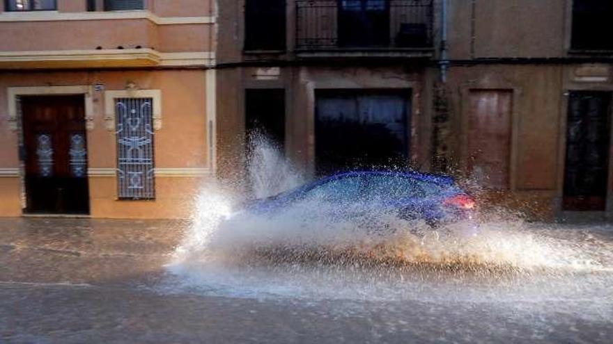 Un vehículo circula por una calle anegada en Castellón. // Efe