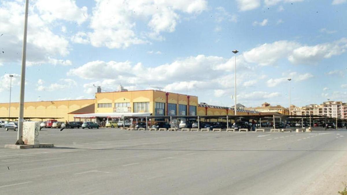 Aparcamiento de la zona comercial de Port Saplaya, con los bloques de apartamentos al fondo.