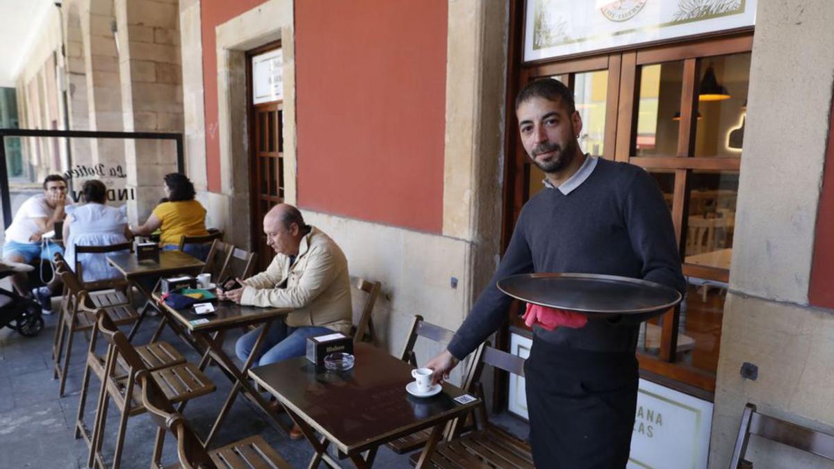 Abel Losada, sirviendo ayer un café en una mesa de su terraza, en la plaza Mayor. | Marcos León