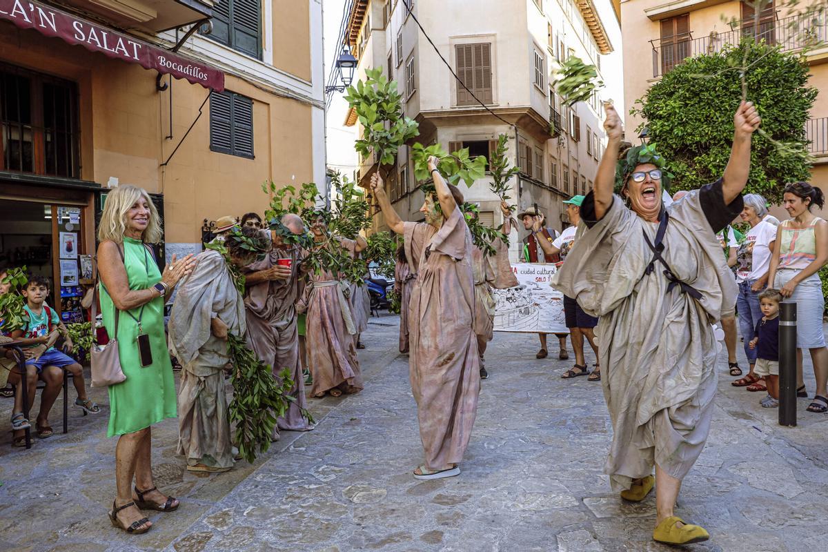 Vecinos de la Calatrava y Canamunt, muchos vestidos de verde y con ramas de árboles, se unen durante sus cercavilas para homenajear a los bellasombras talados en la plaza Llorenç Villalonga.