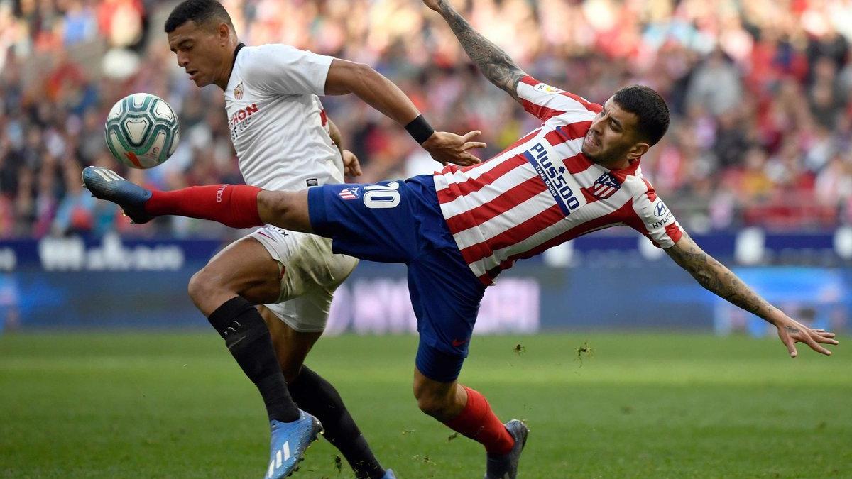 El defensa del Sevilla Diego Carlos (L) compite con el delantero del Atlético de Madrid Angel Correa durante el partido de fútbol de la liga española entre el Club Atlético de Madrid y el Sevilla FC en el estadio Wanda Metropolitano de Madrid.