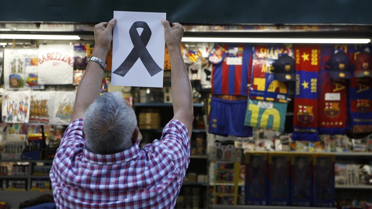 Un quiosquero de la Rambla, coloca un lazo simbólico en memoria de las víctimas. 