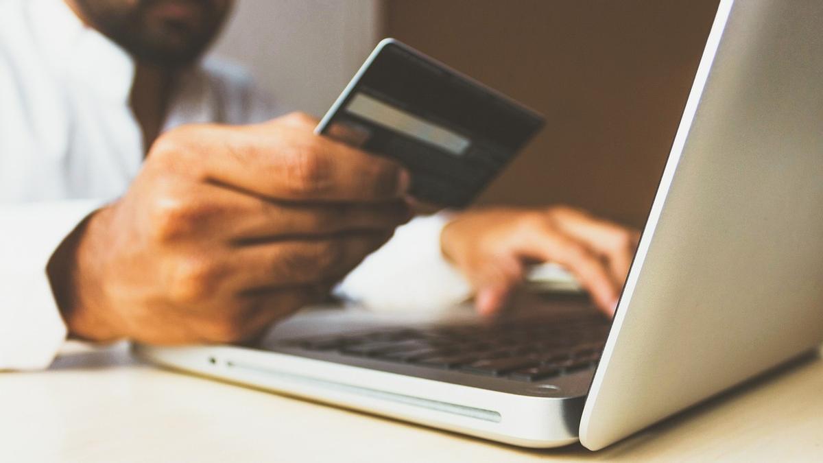 Un hombre realiza un pago por internet con una tarjeta bancaria Un hombre realiza un pago por internet con una tarjeta bancaria