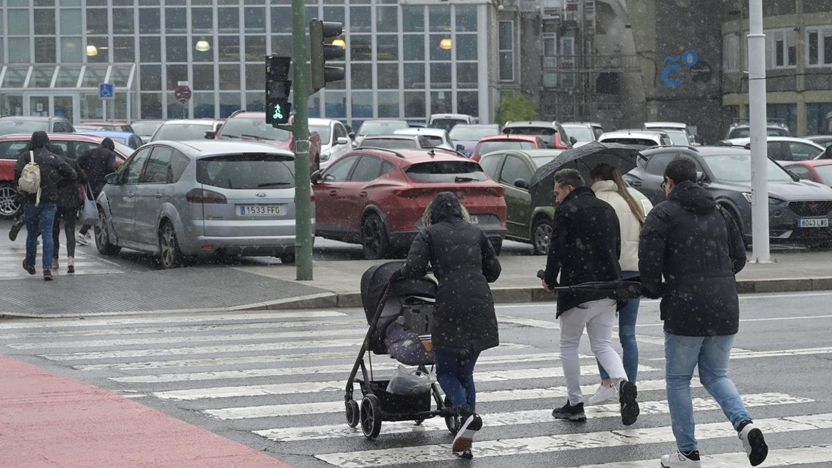Varias personas cruzan un paso de peatones tratando de refugiarse de la lluvia
