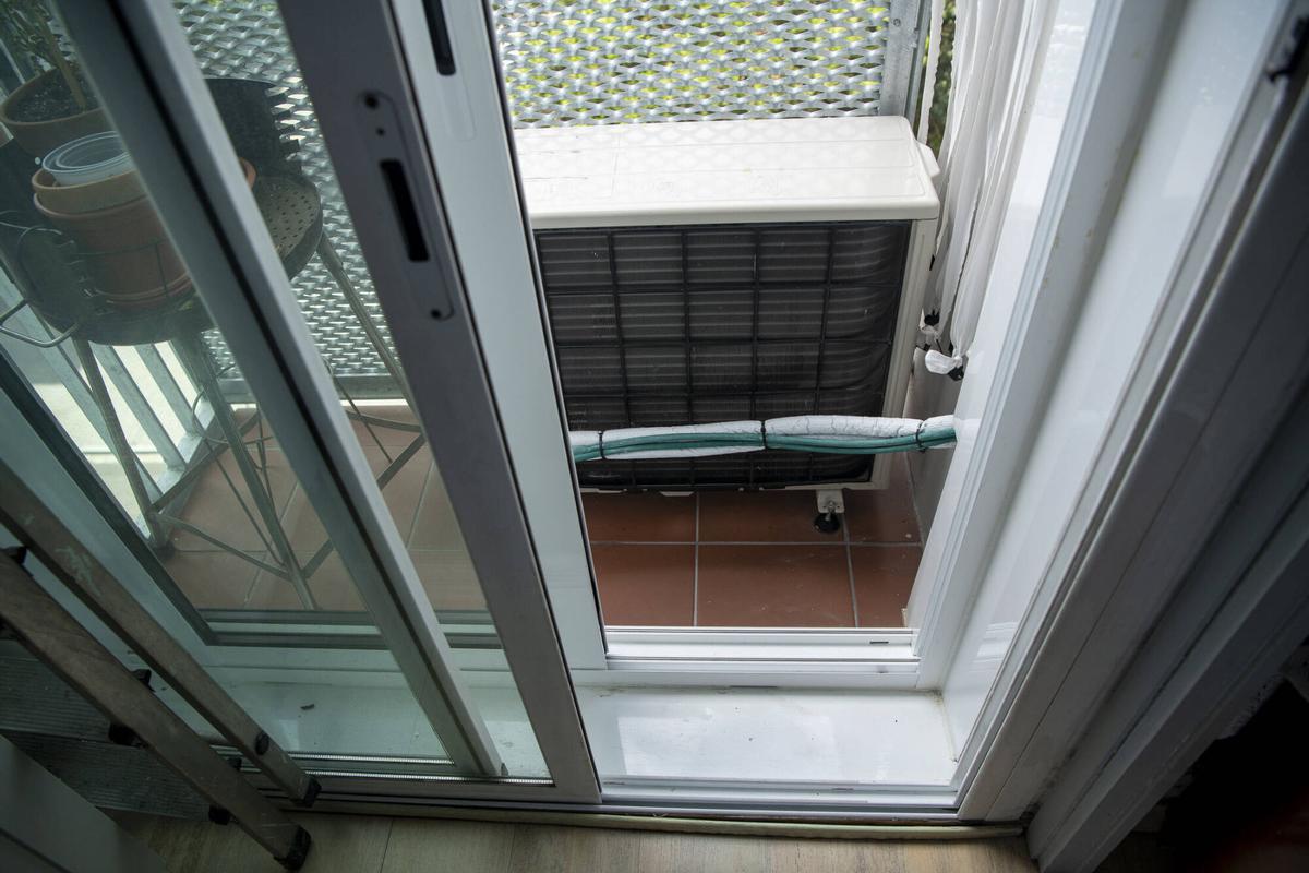 Compresor del sistema de aerotermia instalado en el balcón. Vecinos y vecinas denuncian que el aparato y las puertas dobles que les han colocado a modo de aislante térmico, inutilizan los balcones. Bloque de vivienda pública de la calle Tiana. Barcelona, 21 de agosto de 2026. Foto: Belén González / EP