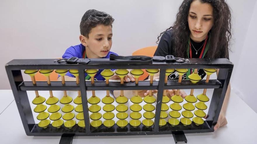 Mohamad y Bayán Almasri Alhalabi, de 10 y 15 años, están concentrados y calculando con un ábaco cuánto es 32 + 15 + 25 - 12 + 5.