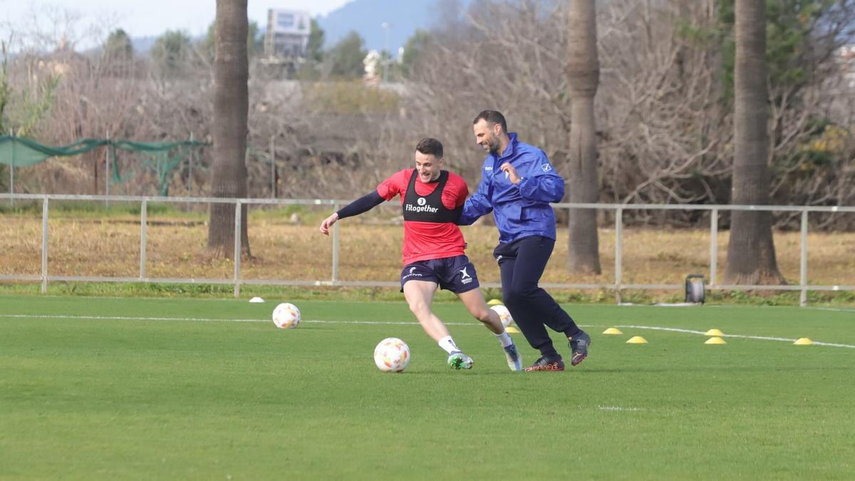 Ekaitz Jiménez controla un balón junto a Miguel Ángel Moriana, recuperador físico del club.