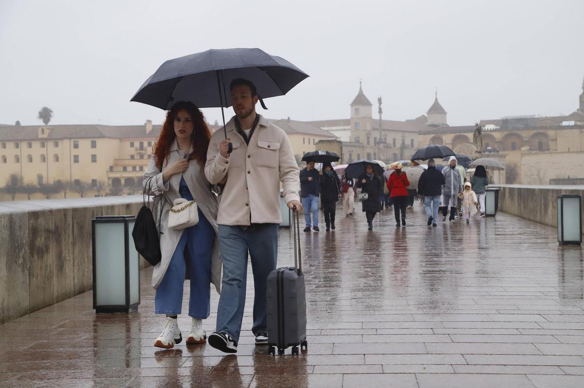 Una pareja por el Puente Romano en un día de intensa lluvia.