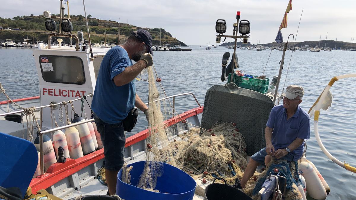Isca Garcia, pescador de la Confraria de Pescadors de Cadaqués, recollint la xarxa tornant d&#039;en mar, amb Benido Descamps