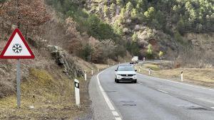 Diversos vehicles circulant per la carretera N-260 al Pont de Bar (Alt Urgell) on hi ha un cartell que avisa del perill de gelades i diversos clots a la calçada