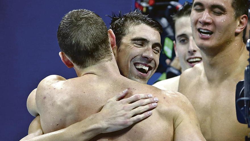 Michael Phelps se abraza a sus compañeros del relevo 4x100 tras conseguir el oro.