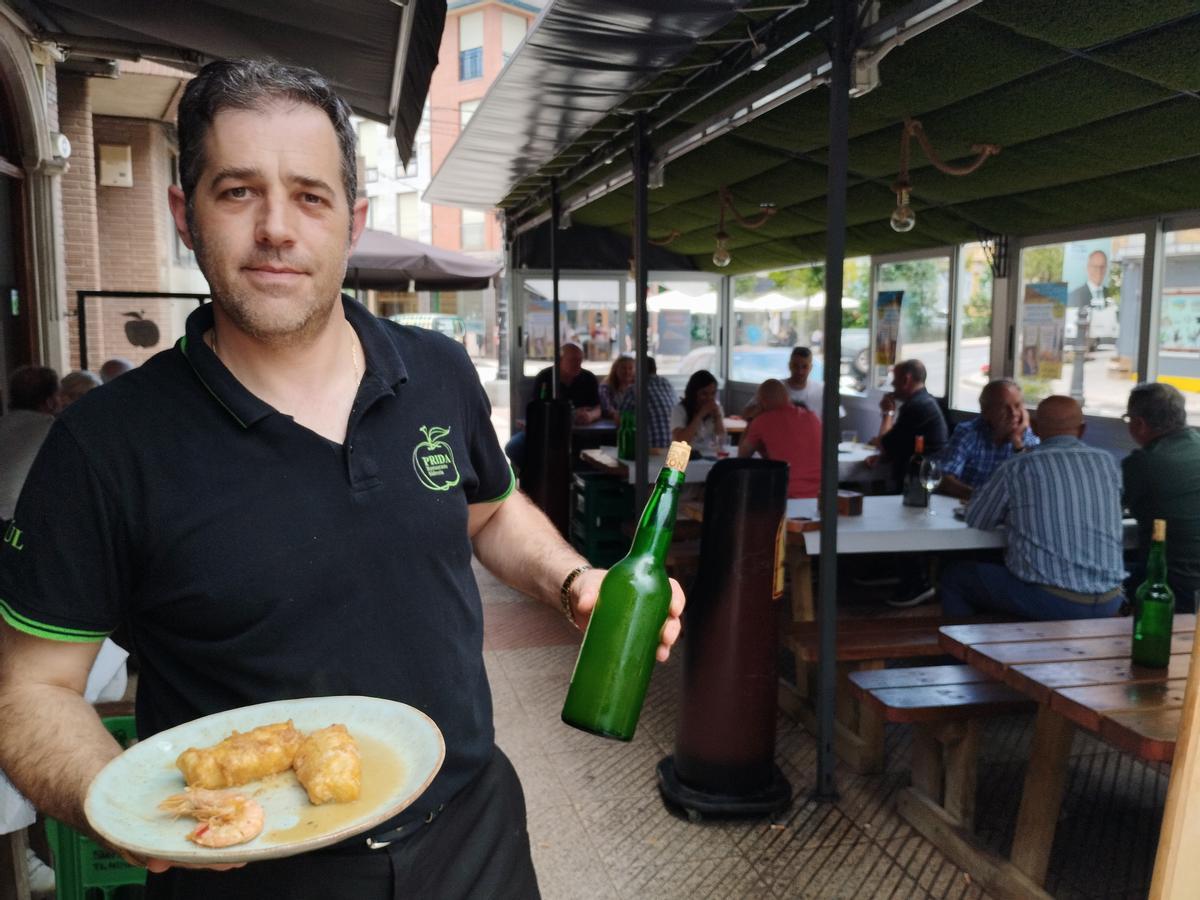 Saúl Moro a punto de servir una merluza a la sidra con una botella de la bebida regional.