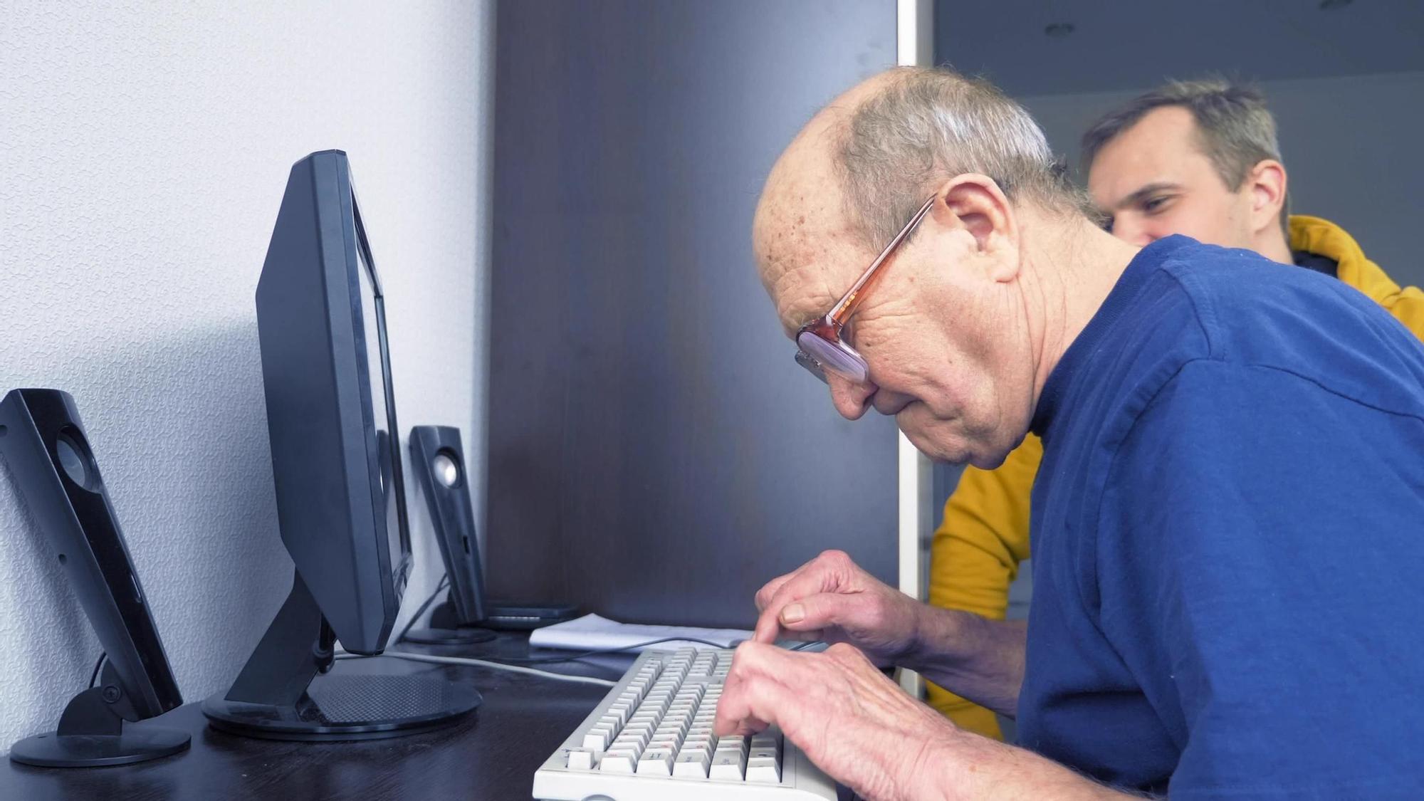 Un hombre mayor utiliza el ordenador en una formación contra la brecha digital.