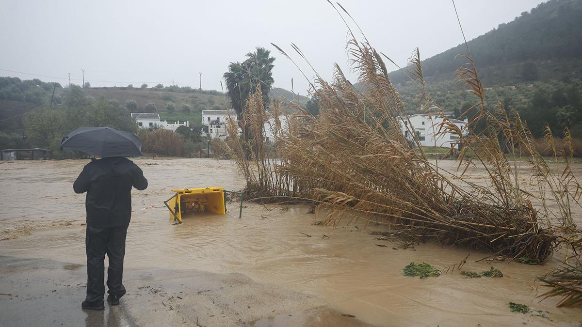 Un hombre junto a la carretera de acceso a Huerta de la Cueva, cortada como consecuencia del paso de la borrasca Leonardo por la provincia de Málaga.
